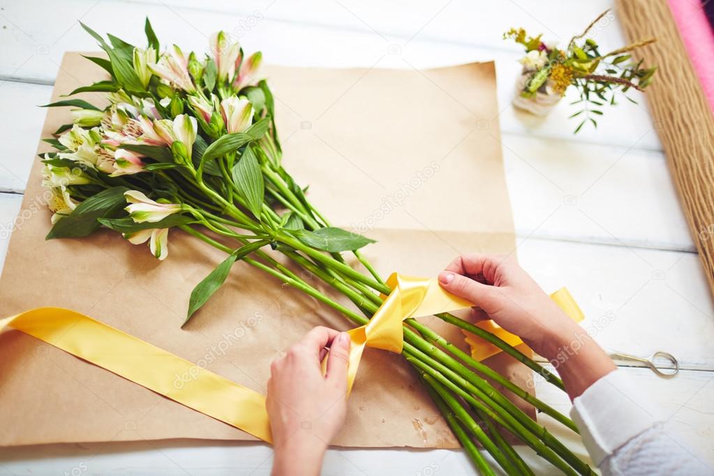 florist tying up bouquet with ribbon