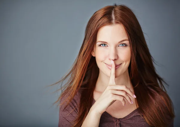 Vrouw haar wijsvinger houden door lippen — Stockfoto