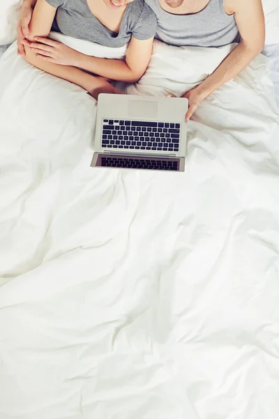 Pareja sentada en la cama con portátil — Foto de Stock