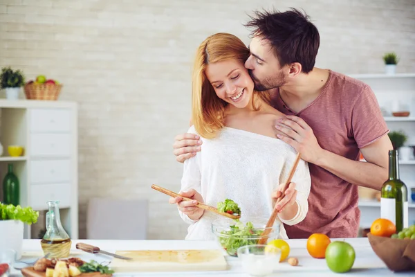 Мужчина целует свою жену на кухне — стоковое фото