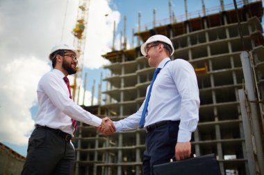architects handshaking near new construction