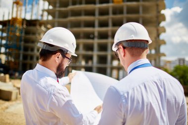 architects in helmets discussing sketch