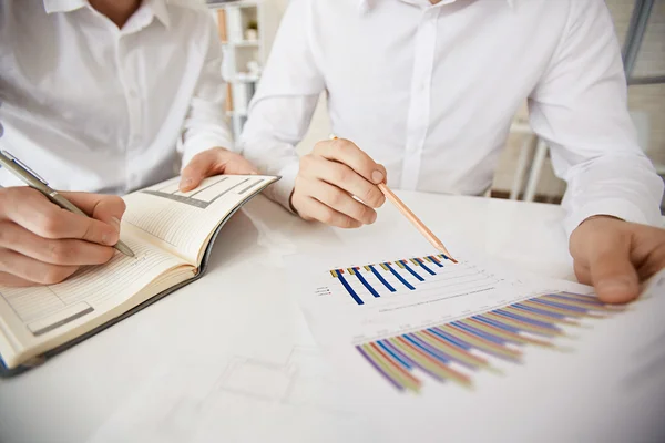 Businessman with pencil pointing at data with colleague — Stockfoto