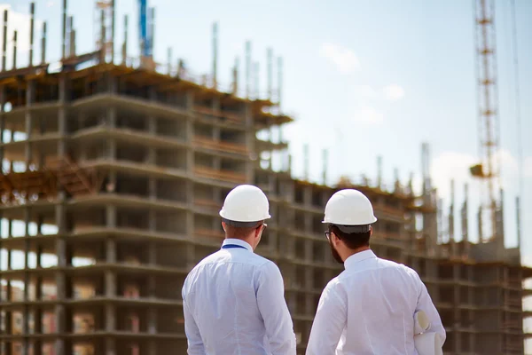 Architekten in Helmen stehen vor Neubauten — Stockfoto