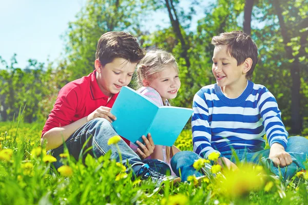 Kinder mit Buch auf Rasen — Stockfoto