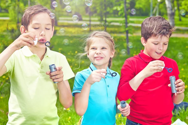 Friends blowing soap bubbles in park — Stock Photo, Image