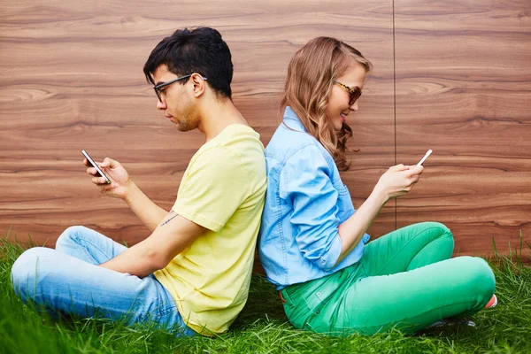 Пара подростков со смартфонами — стоковое фото
