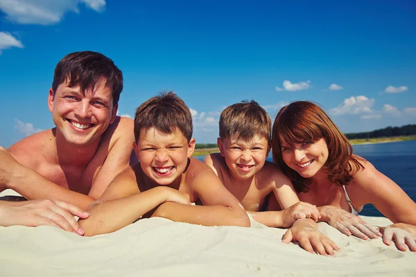 Family sunbathing on sandy beach Stock Image