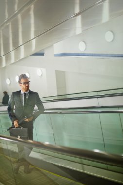 evrak çantası ve yürüyen merdiven şemsiyesi ile işadamı