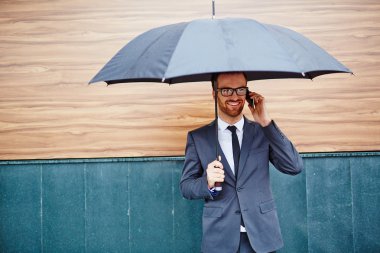 şemsiyesi altında telefonda konuşan işadamı