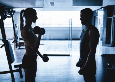 eğitmen ile dumbbells ile egzersiz yaparak kadın