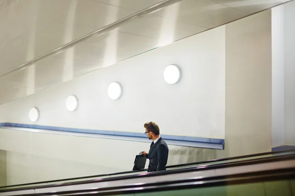 Hombre de negocios con maletín en escalera mecánica —  Fotos de Stock