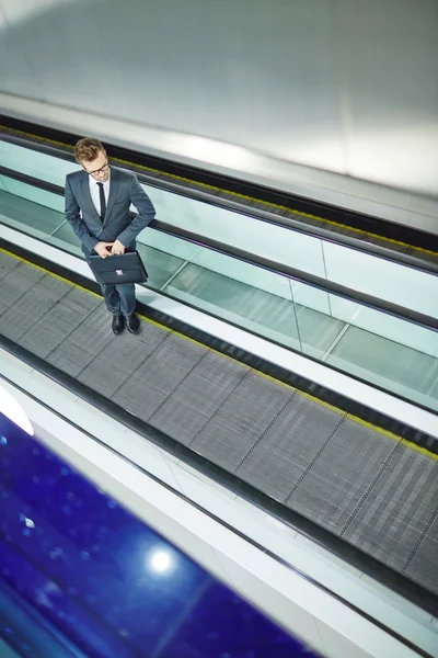 Businessman with briefcase standing on escalator — Stock Photo, Image