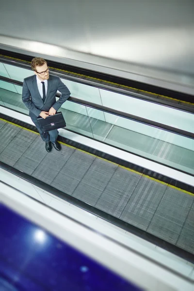 Geschäftsmann mit Aktentasche steht auf Rolltreppe — Stockfoto