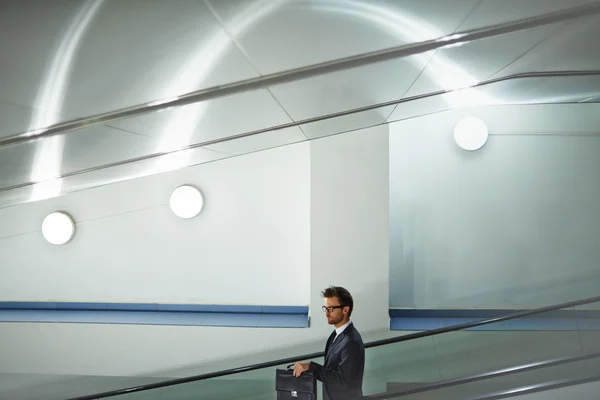 businessman with briefcase moving on escalator