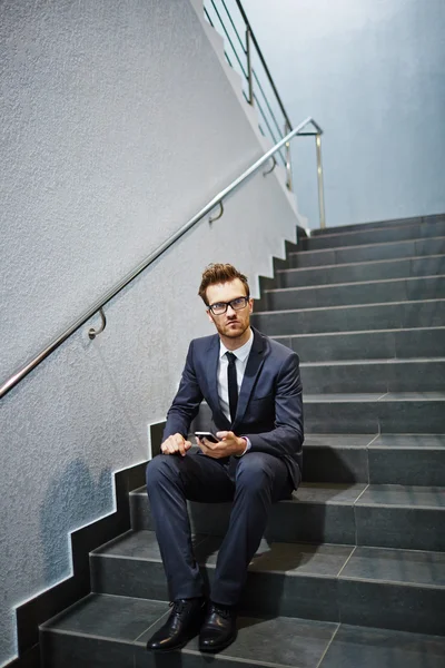 Empresario con celular sentado en las escaleras — Foto de Stock