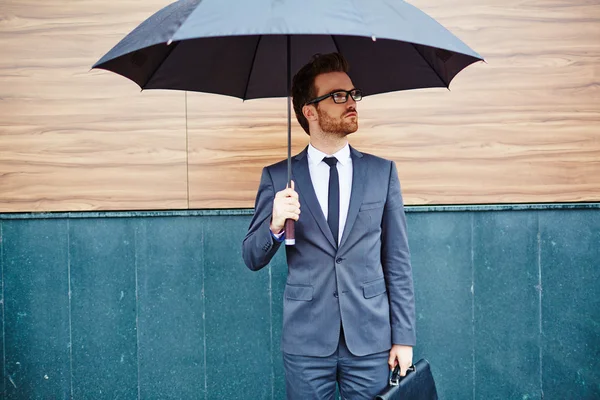 Homem de negócios com pasta sob guarda-chuva — Fotografia de Stock