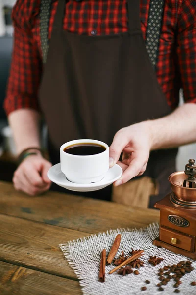 Barista sosteniendo una taza de café negro — Foto de Stock