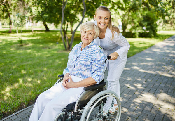 Healthcare assistant and aged woman in a wheelchair