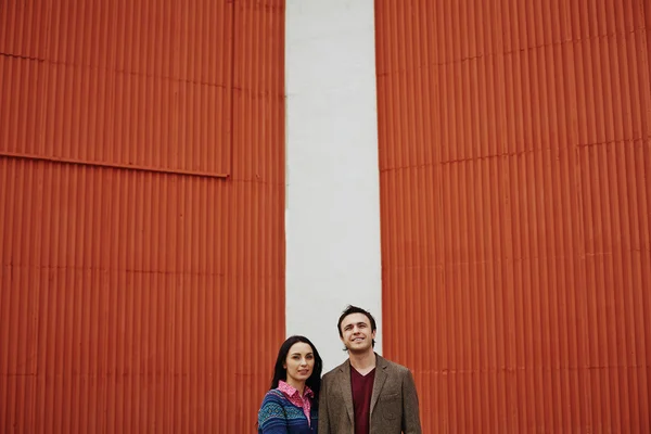 Pareja de casualwear de pie junto a la pared roja — Foto de Stock