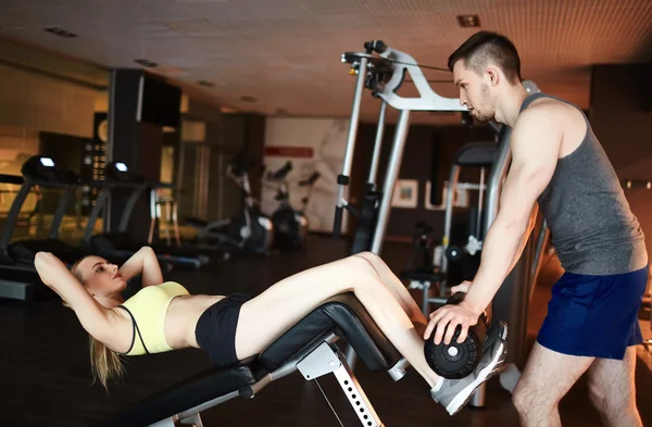 Treinador ajudando a jovem mulher a fazer flexões — Fotografia de Stock