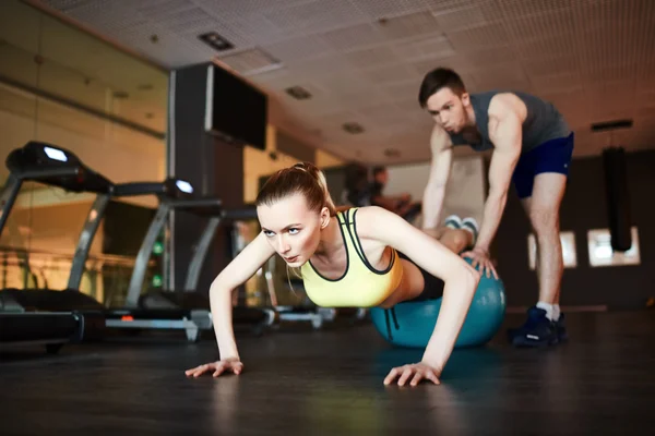 Mujer haciendo flexiones en la pelota con entrenador —  Fotos de Stock