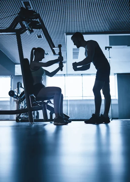 Mujer haciendo ejercicio con entrenador en el gimnasio — Foto de Stock