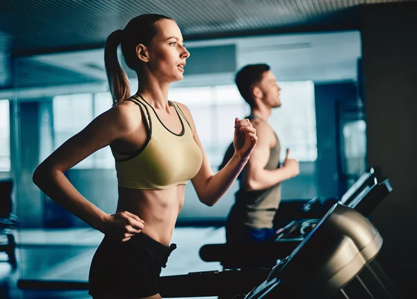 Mujer y hombre corriendo en cinta de correr — Foto de Stock