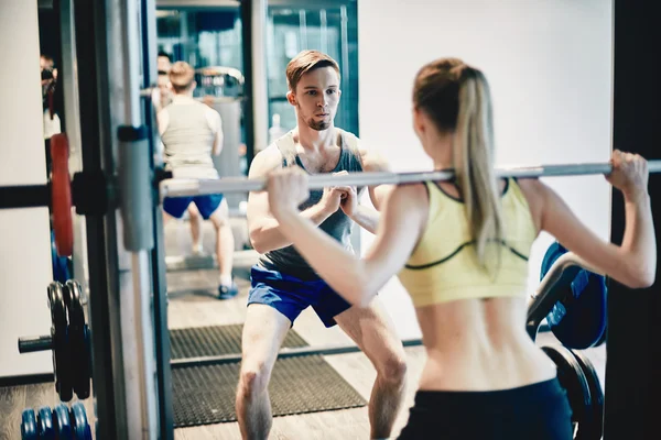 Trainer waarop vrouw hoe om gewicht te heffen — Stockfoto