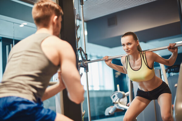 woman looking at trainer and  lifting weight