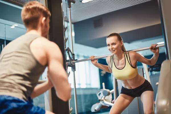 Woman looking at trainer during weightlifting — Stock Photo, Image