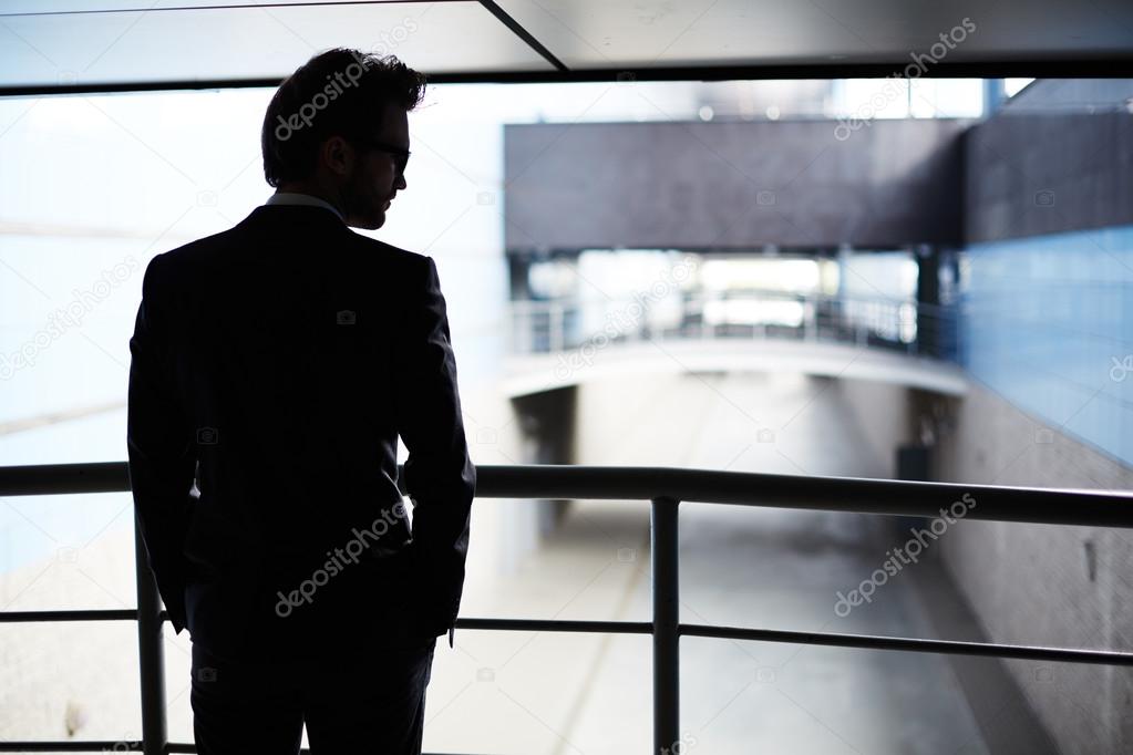 young businessman silhouette standing by railings