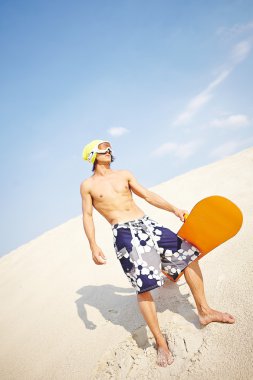 sandboard kum plajı üzerinde olan adam