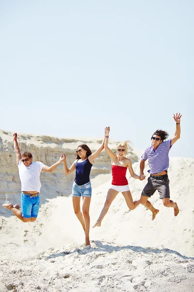 Young people  jumping over sandy beach — Stock Photo, Image