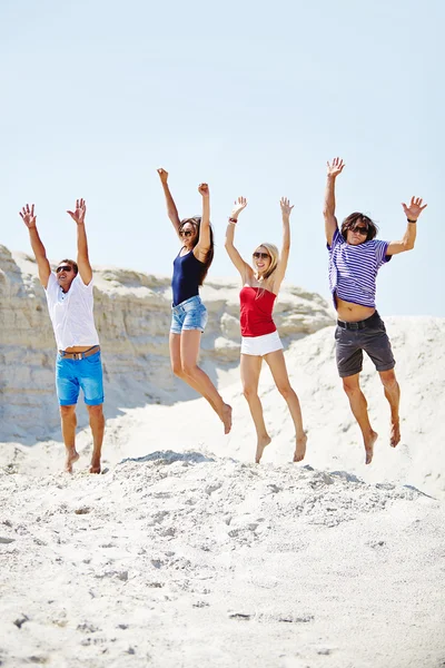 Young people  jumping over sandy beach — Stock Photo, Image