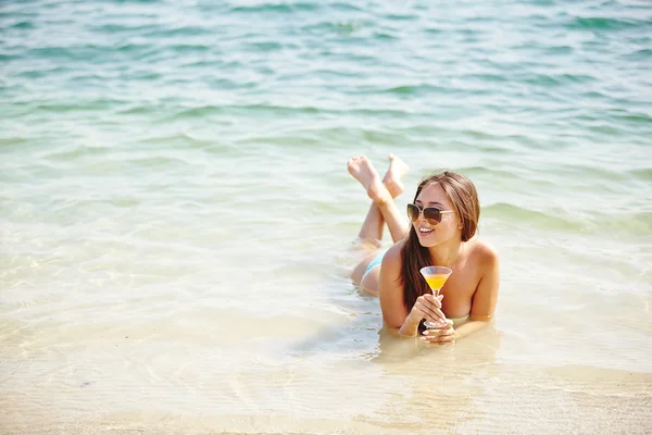 Woman with cocktail lying in water — Stock Photo, Image