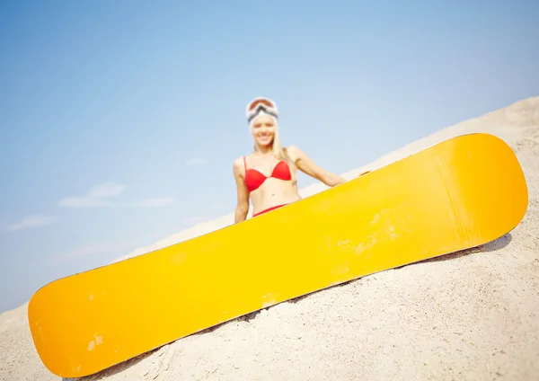 Snowboard on sand with woman on background — Stock Photo, Image