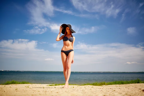 Kobieta w bikini i kapelusz na plaży — Zdjęcie stockowe