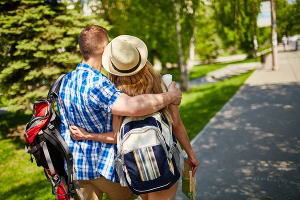 Couple with backpacks hugging and walking — Stock Photo, Image