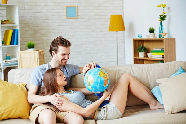 Casal com globo escolhendo onde passar férias — Fotografia de Stock