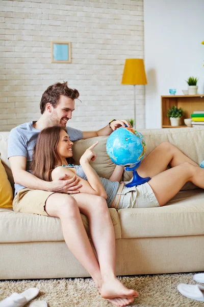 Casal com globo escolhendo onde passar férias — Fotografia de Stock