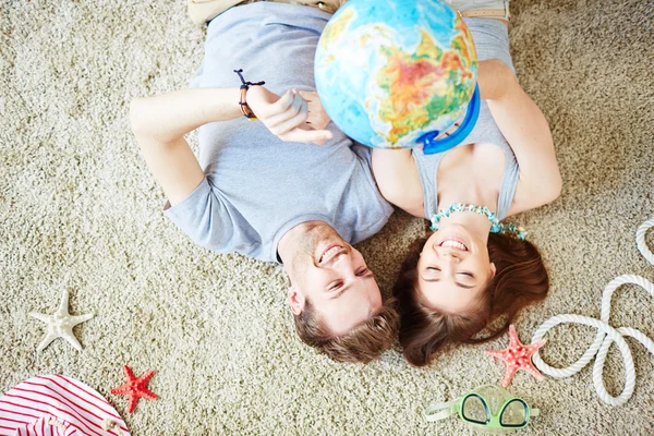 Couple with globe lying on the floor — Stock Photo, Image