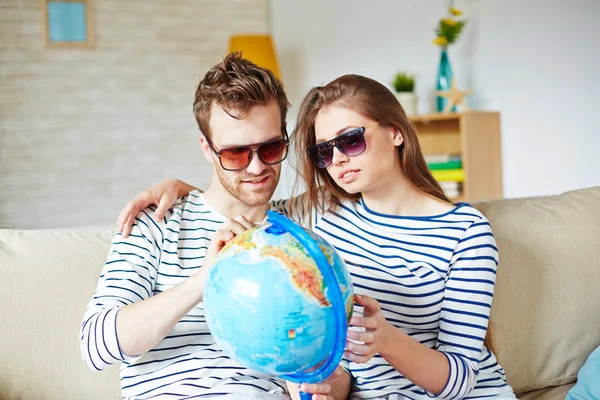 Couple in sunglasses holding globe — Stock Photo, Image