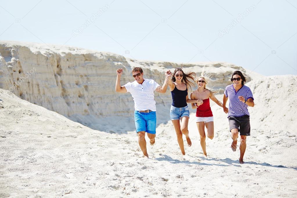 People running down sandy beach Stock Photo by ©pressmaster 76981689