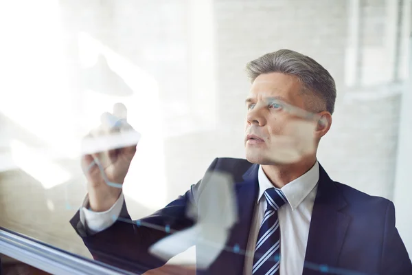 Businessman standing by transparent board — Stock Photo, Image