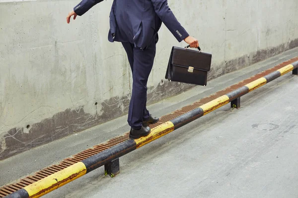 Empresario equilibrio en amarillo y negro carretera bordillo — Foto de Stock