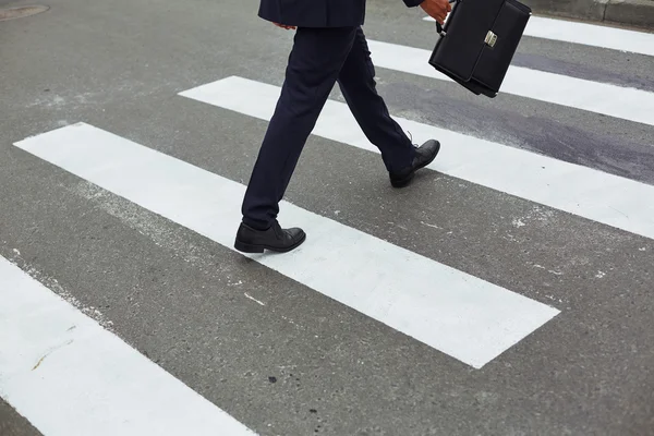 Businessman with briefcase crossing road — Stock Photo, Image