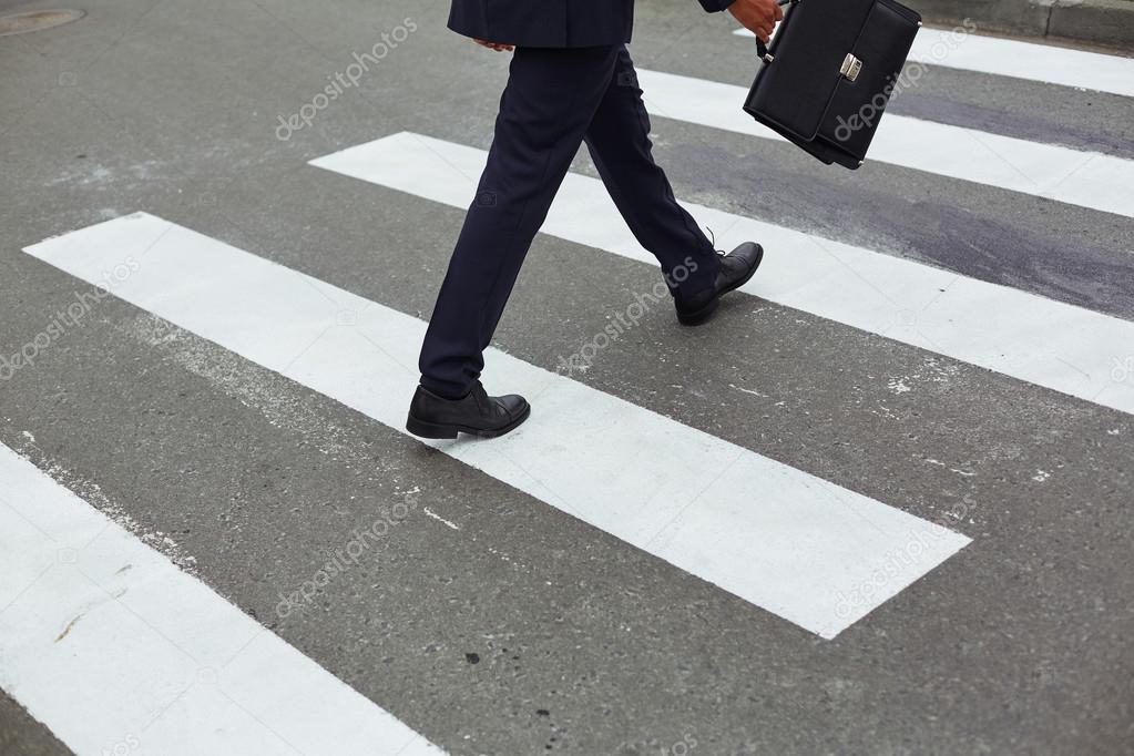 businessman with briefcase crossing road