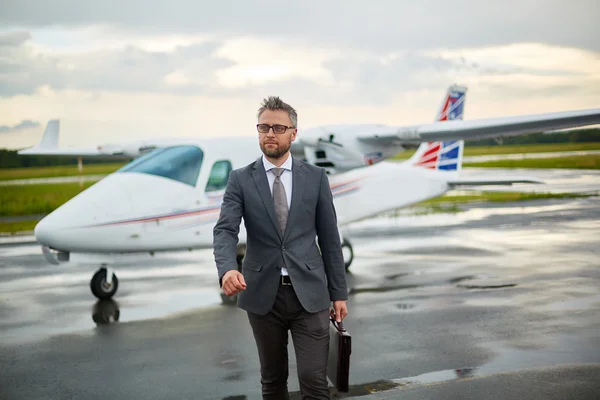 Businessman with briefcase walking from airplane — Stock Photo, Image