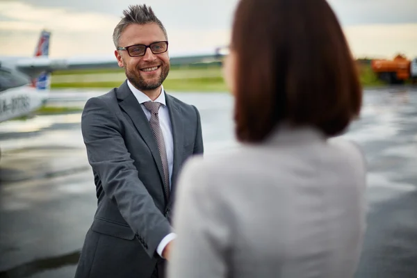 Hombre de negocios saludando a su pareja a su llegada —  Fotos de Stock